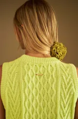 Chaleco de punto sin mangas en color verde lima, con diseño de ochos en el frente y cuello redondo tejido en rib.
