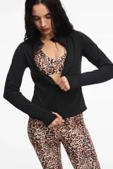 Campera deportiva de cuello alto con cierre frontal de doble cursor. Presenta un corte ajustado que realza la silueta, bolsillos laterales con cierre y mangas largas con puños con abertura para el pulgar.