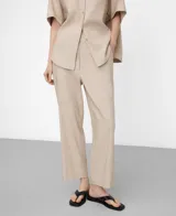 Pantalón de pierna recta y largo tobillero, color beige con diseño microdibujo. Cuenta con cinturilla elástica en los costados, bolsillos laterales y un bolsillo de vivo con botón en la espalda.