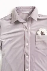 Pijama de dos piezas color rosa pálido, confeccionado en terciopelo. La camisa es de manga larga con botones frontales y bolsillo en el pecho. El pantalón es de corte recto con cintura elástica.