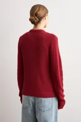 Chaqueta tejida de punto acanalado en color azul marino, con cuello redondo, cierre frontal de botones metálicos y dos bolsillos delanteros aplicados.
