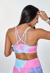 Conjunto deportivo de dos piezas compuesto por un top deportivo de escote redondo y un short ciclista de tiro alto. Ambas prendas presentan un diseño estampado con efecto tie-dye en tonos azul, rosa y violeta.