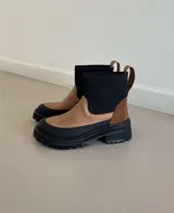 Bota de cuero color marrón claro con caña de neopreno elastizado color negro y suela track color negro.