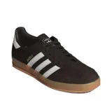 Championes Adidas Gazelle Indoor, modelo de corte clásico y retro fabricado en gamuza de color marrón oscuro, con las tres franjas características de la marca y la lengüeta del talón en color blanco. Incluye la inscripción "GAZELLE" en letras doradas en el lateral y suela de caucho translúcido tipo caramelo.