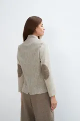 Chaqueta corta color marrón con cuello solapa y diseño con patchwork de telas. Manga larga con detalle de coderas aplicadas. Cierre frontal mediante botones y bolsillos ojal. Con forro.