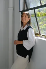 Chaleco de punto negro con escote en V, sin mangas y aberturas laterales en el ruedo.