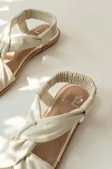 Sandalias chatitas de cuero en tono nude, con diseño de tiras cruzadas en el empeine y elástico en el talón para mayor ajuste. Presentan una plantilla acolchada y detalles en cuero charolado en la parte posterior.