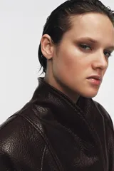 Chaqueta de Zara Woman Collection confeccionada en tejido efecto piel con textura granulada. Presenta cuello solapa, manga larga y cierre frontal con cinturón ajustable anudado a la cintura. Incluye forro interior.