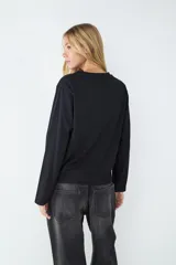 Remera básica negra de manga larga con cuello redondo y corte regular, confeccionada en tejido de punto liso de algodón.