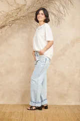 Pantalón de jean celeste de corte ancho con apliques bordados y desflecados.