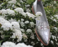 Mocasines de cuero plateado con acabado texturado, diseño clásico con costuras visibles y vira de suela natural cosida. Cuenta con taco plano de 2 cm y plantilla anatómica.