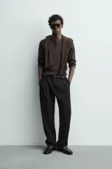Pantalón straight fit color negro confeccionado en tejido con lana, con detalle de pliegues en el delantero, bolsillos frontales y traseros, y cierre frontal con cremallera y botón.
