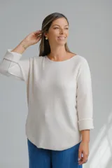 Sweter de punto color crudo, con escote a la base y mangas tres cuartos con dobladillo.