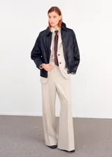 Pantalón de vestir de tiro medio, color beige, de corte recto y amplio con pinzas frontales.