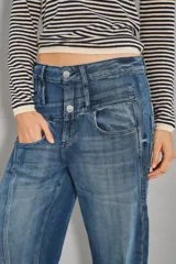 Jean de tiro medio con diseño de doble cintura superpuesta y pierna recta. Confeccionado en denim azul oscuro, presenta cierre y botón metálico, con costuras verticales decorativas en el frente.