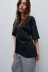 Remera de manga corta color blanco con cuello redondo y detalle de frunce lateral que aporta movimiento y una silueta entallada.