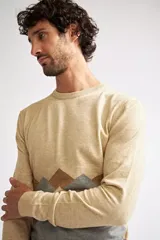 Sweater de punto con diseño color block, combinando azul marino en la parte superior, un patrón geométrico en tonos bordó y azul en el centro, y color camel en la parte inferior. Presenta cuello redondo y mangas largas.