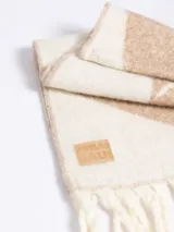 Bufanda de lana con diseño geométrico en tonos gris y marrón, con flecos en los extremos y etiqueta de marca cosida.