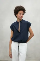 Camisa azul marino con cierre frontal de botones y dobladillo ajustable con cordones de tela.