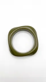 Pulsera rígida de acrílico en tono beige marmolado, con diseño asimétrico.