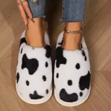 Pantuflas sin talón confeccionadas en algodón afelpado y piel sintética, con divertido estampado de manchas de vaca en tonos blanco y marrón, y suela de PVC.