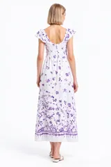 Vestido largo de algodón blanco con estampado floral en tonos violeta, diseño holgado, escote bote con volados y detalle fruncido en el pecho.