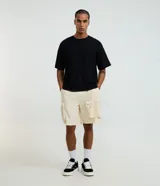 Bermuda baggy cropped de color beige, confeccionada en poliéster, con cintura elástica y múltiples bolsillos funcionales estilo cargo.