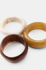 Pack de tres pulseras rígidas de resina en tonos tierra, con acabados lisos y marmolados.