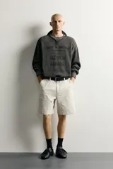 Sweater relaxed fit de algodón color gris con efecto lavado, cuello redondo, manga larga y diseño de textos estampados a contraste en el frente.