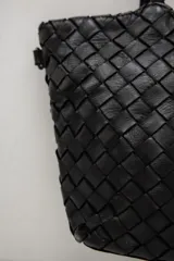 Cartera de cuero marrón con diseño trenzado y asas de hombro trenzadas.