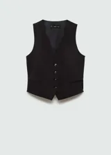 Chaleco de estilo sastre en color negro, con cuello en pico, cierre frontal de botones y dos bolsillos de ribete delanteros. Presenta un diseño recto y forro interior.