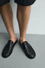 Mocasines destalonados de cuero color negro, de diseño liso con detalle de antifaz en el empeine y horma redonda.