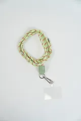 Correa para celular de cuerda color verde claro con detalles en rojo, con terminaciones metálicas y aplique de cuero sintético verde que conecta con un mosquetón y una placa transparente para sujetar el dispositivo.