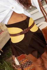 Cinturón de diseño escultórico con base acolchada en color amarillo y correa de cuero marrón con hebilla metálica dorada.