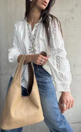 Camisa blanca de manga larga con detalles de encaje y diseño abotonado en la parte delantera.