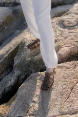 Sandalias de cuero color marrón, estilo romano con tiras entrelazadas, punta cuadrada y cierre de hebilla metálica en el tobillo.