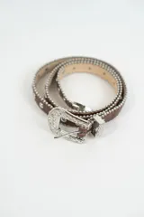 Cinturón marrón con tachas plateadas y hebilla metálica labrada.