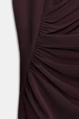 Vestido midi de color negro, con cuello subido y diseño sin mangas. Presenta un detalle de drapeado lateral en la parte delantera y cierre de cremallera oculta en la espalda.