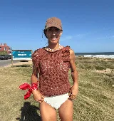 Musculosa tejida en punto calado, color violeta, con diseño sin mangas y detalle de flecos en los hombros.