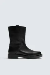 Bota de caña alta confeccionada en piel con acabado granulado y suela de goma con volumen a tono.