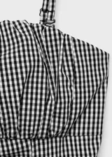 Vestido midi de corte evasé con estampado de cuadros vichy en blanco y negro. Presenta un diseño sin mangas con tirantes finos ajustables, escote recto con detalle fruncido y cierre de cremallera lateral.