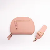 Bandolera de cuero sintético color rosado, con diseño semicircular, cierre frontal con tirador de cordón y herrajes metálicos dorados. Incluye correa ajustable extraíble.