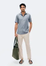 Camisa de manga corta celeste con estampado de micromercado, cuello camisero, cierre frontal con botones y un bolsillo ojal en el pecho.