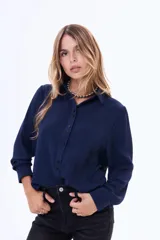 Camisa de manga larga color azul marino, con cuello clásico, cierre frontal de botones y un bolsillo en el pecho. Presenta un diseño de líneas simples y calce cómodo.