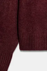 Jersey de punto color vino tinto, de cuello redondo y manga larga, con acabado acanalado (rib) en puños, cuello y bajo.