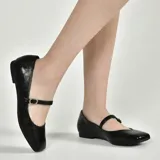 Zapato de charol negro con correa sobre el empeine y hebilla con strass.