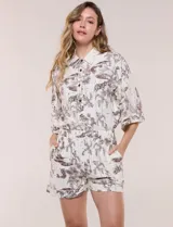 Conjunto de dos piezas de algodón y lino, con estampado estilo Toile de Jouy en color marrón sobre fondo off-white. Incluye camisa de manga corta amplia con cuello camisero y short tiro alto con elástico en la cintura y bolsillos.