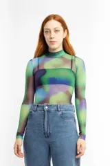 Remera de mesh transparente con cuello alto y estampado abstracto en tonos verde, azul y violeta.