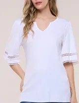 Remera blanca de silueta recta y algodón suave, con escote redondo y pequeña abertura central tipo gota. Presenta mangas de largo intermedio con aplicación horizontal de puntilla calada al tono y ruedo recto con tajos laterales.