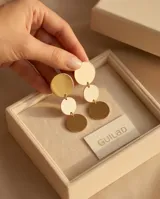 Caravanas colgantes de acero con baño de oro, compuestas por tres círculos planos de diferentes tamaños dispuestos verticalmente.